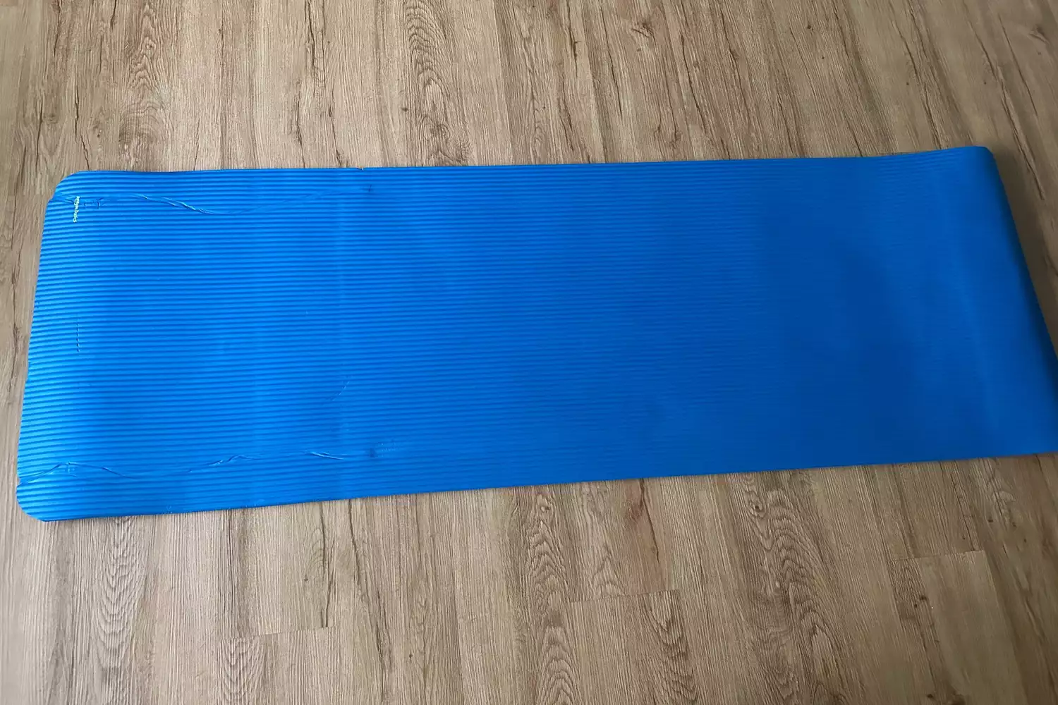 A blue ribbed exercise mat showing visible tears and wear on its surface.