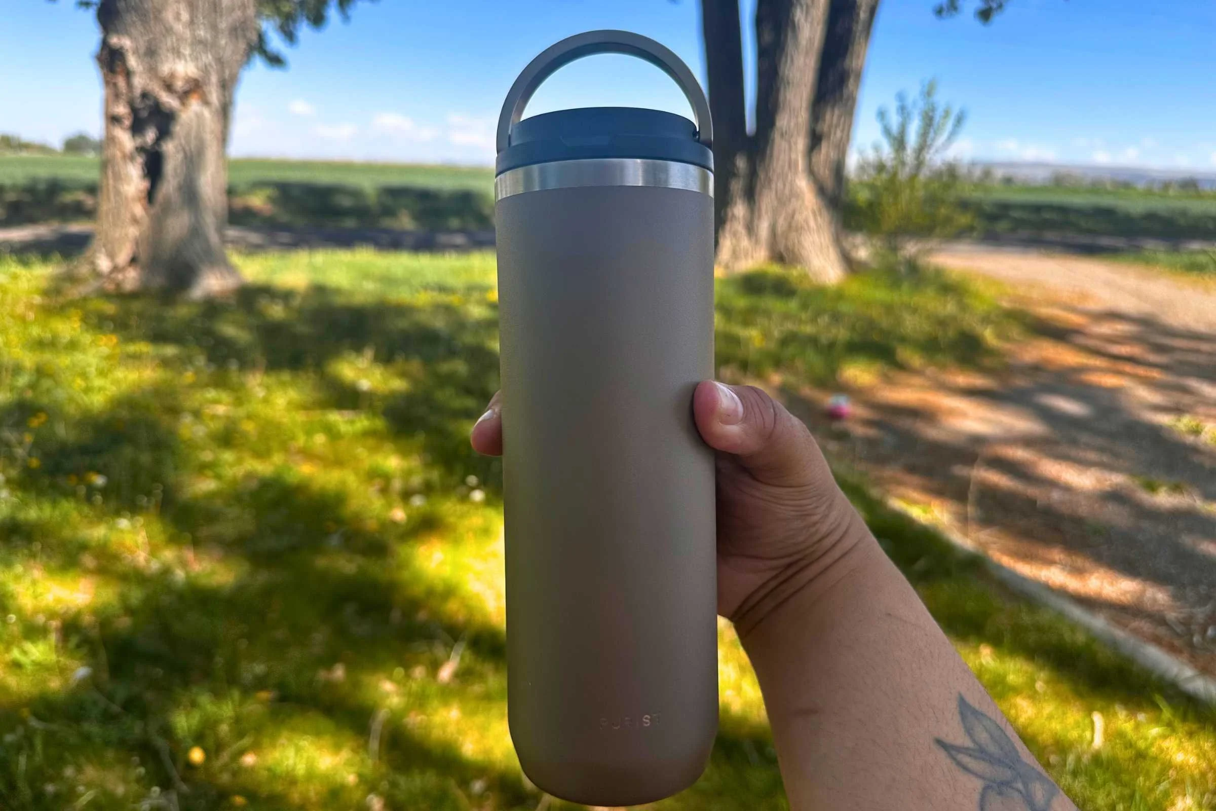 A person holding the ceramic-lined Purist Mover 18 oz insulated tumbler.