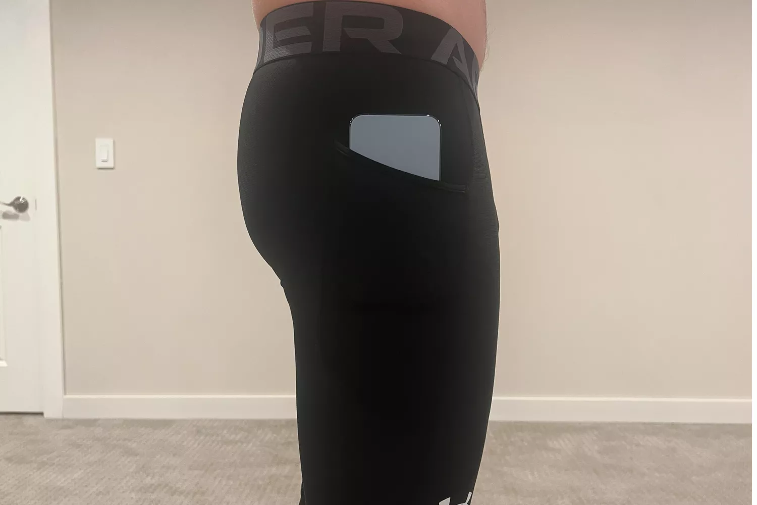 Back view of Under Armour HeatGear leggings with a smartphone tucked into the side pocket.