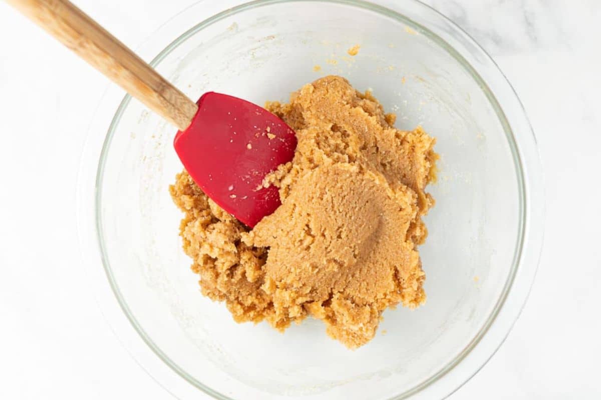 Mixing almond flour cookie dough in a clear glass bowl.