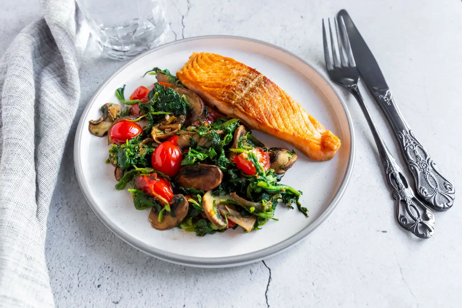 A healthy meal with seared salmon and vegetables on a white plate.