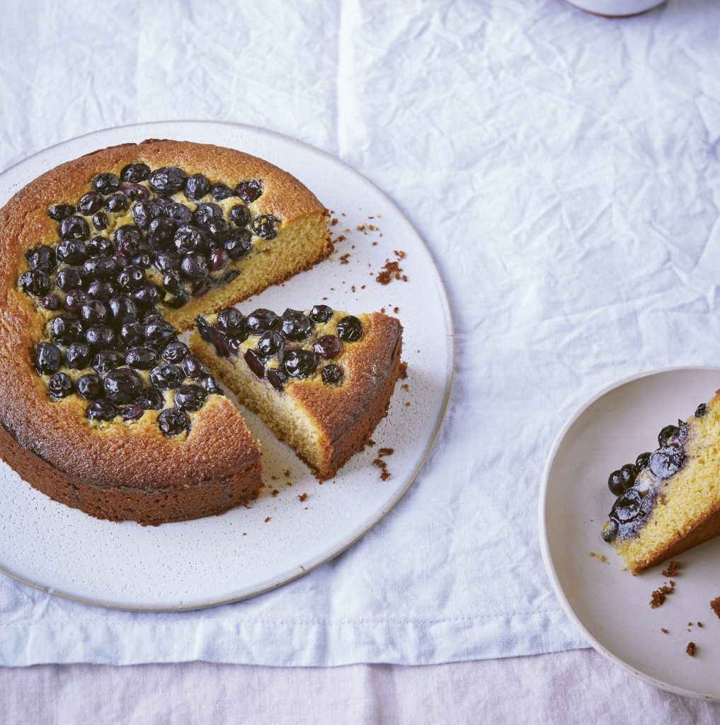 A close-up view of a blueberry and honey cornmeal cake highlighting the moisture-rich crumb and purple berry pockets.