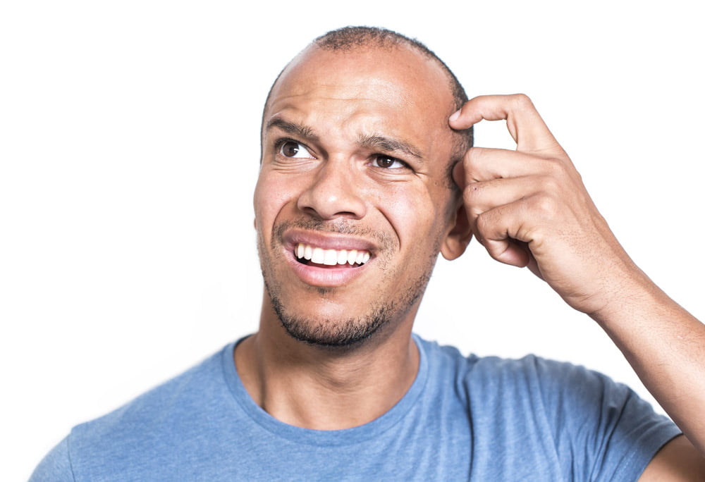 A man looking contemplative while considering different hearing aid options.