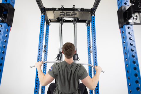 A male athlete demonstrating the correct upright posture and slight lean for a lat pulldown.