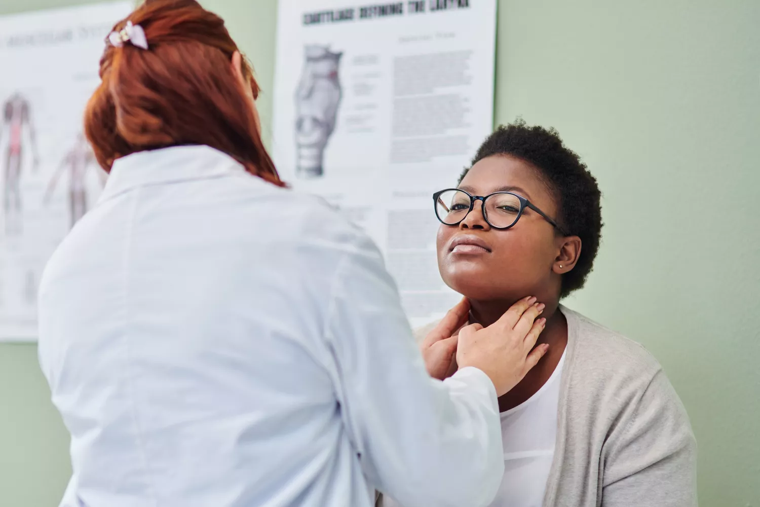 A healthcare provider performing a neck examination on a patient in a clinical office.