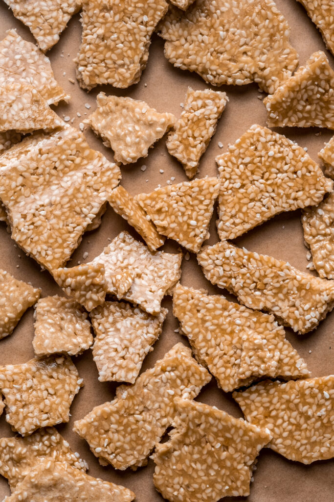 Thin, golden-brown pieces of sesame brittle/florentines.