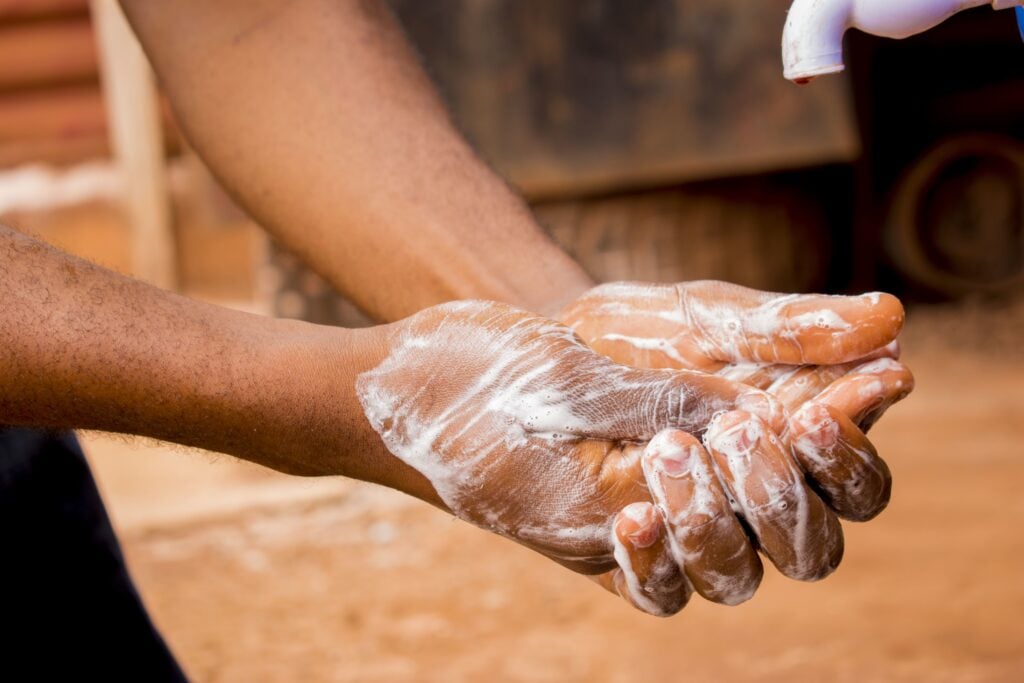 A person washing their hands and a simulated bite area with soap and running water.