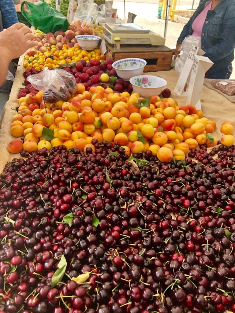Freshly sliced peaches and dark red cherries on a light surface.