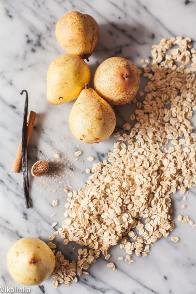 Spiced pear baked oatmeal with a golden crust in a classic white ceramic baking dish.