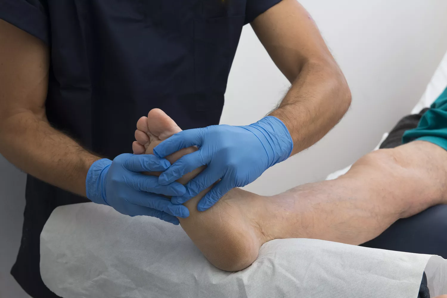 A healthcare professional carefully inspecting a patient's foot during a medical screening.