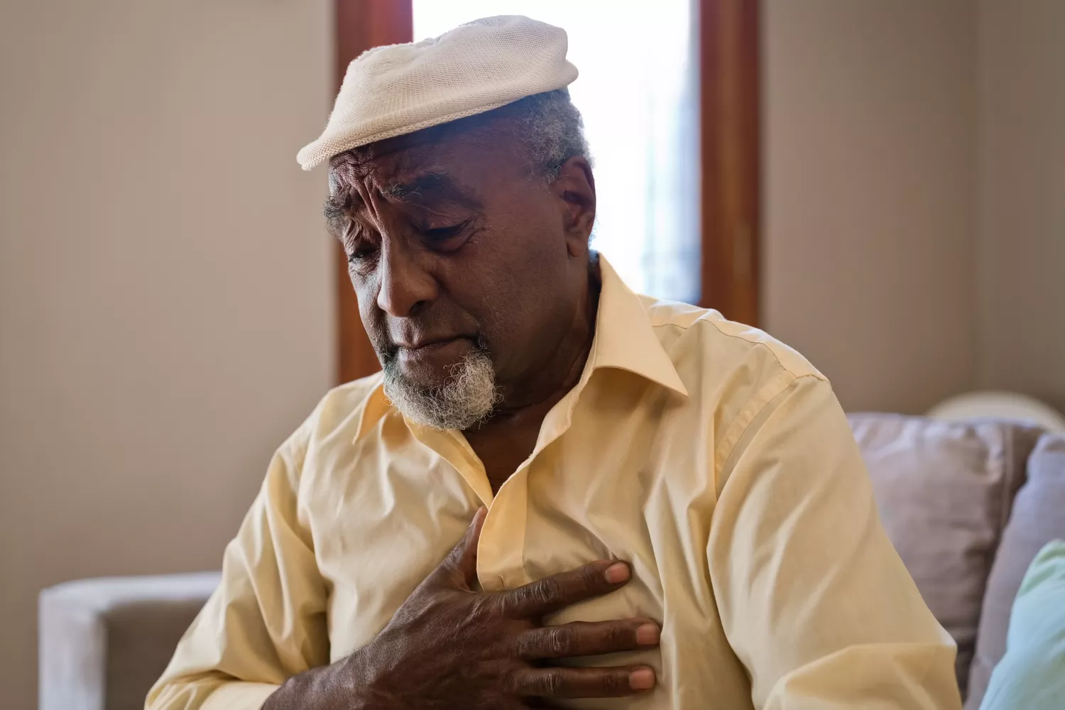 A person holding their hand to their chest in pain, representing the sharp sensation of pericarditis.