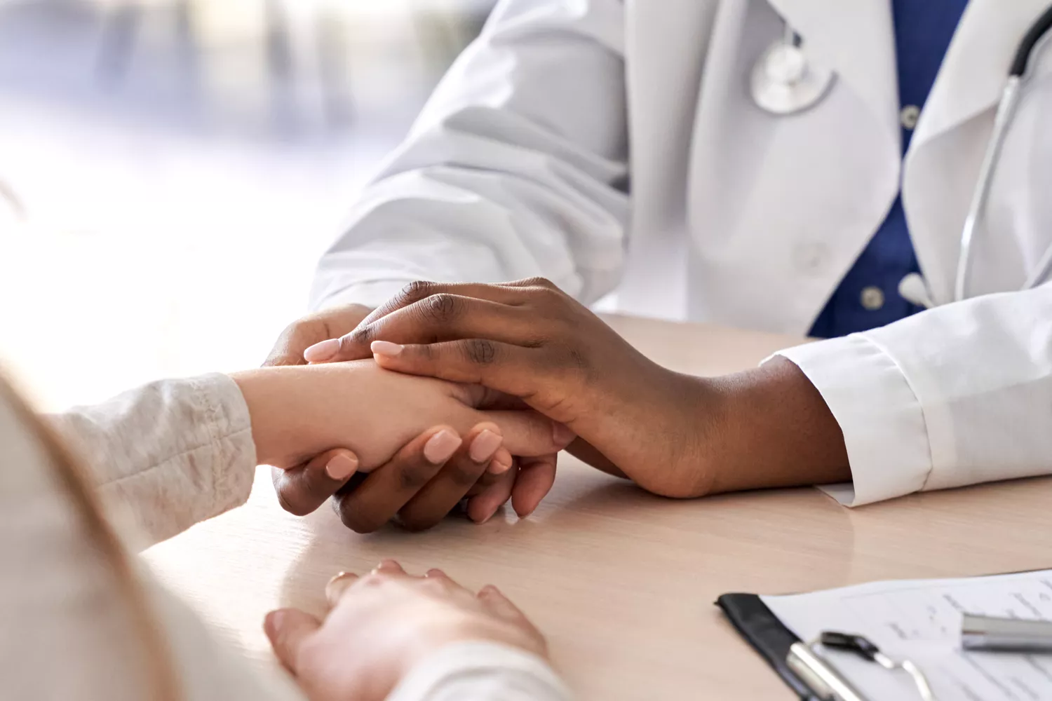 A close-up of a healthcare provider holding a patient's hand in a supportive gesture.