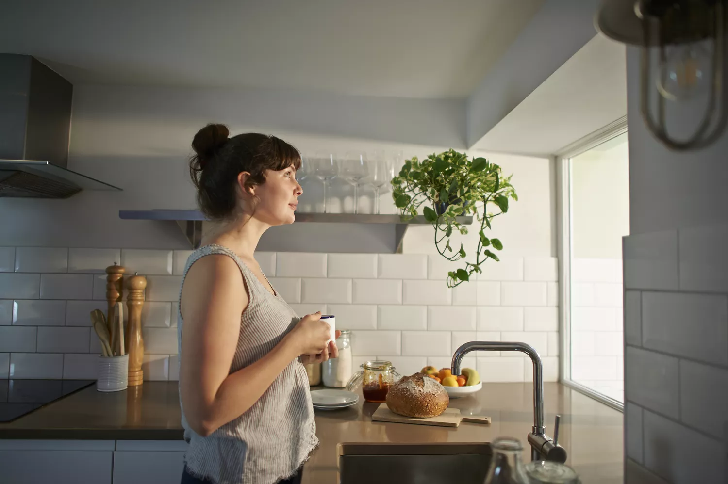 A woman enjoying a cup of coffee in a bright, modern kitchen filled with healthy food items.