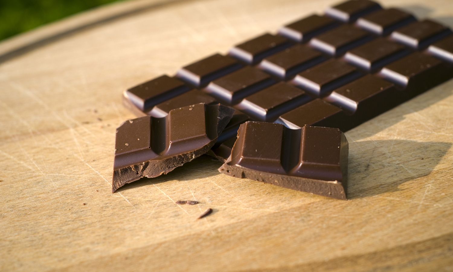 A close-up of a dark chocolate bar broken into pieces.
