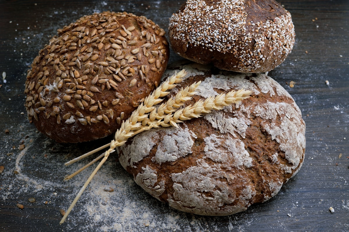 A loaf of multi-grain whole wheat bread on a wooden surface.