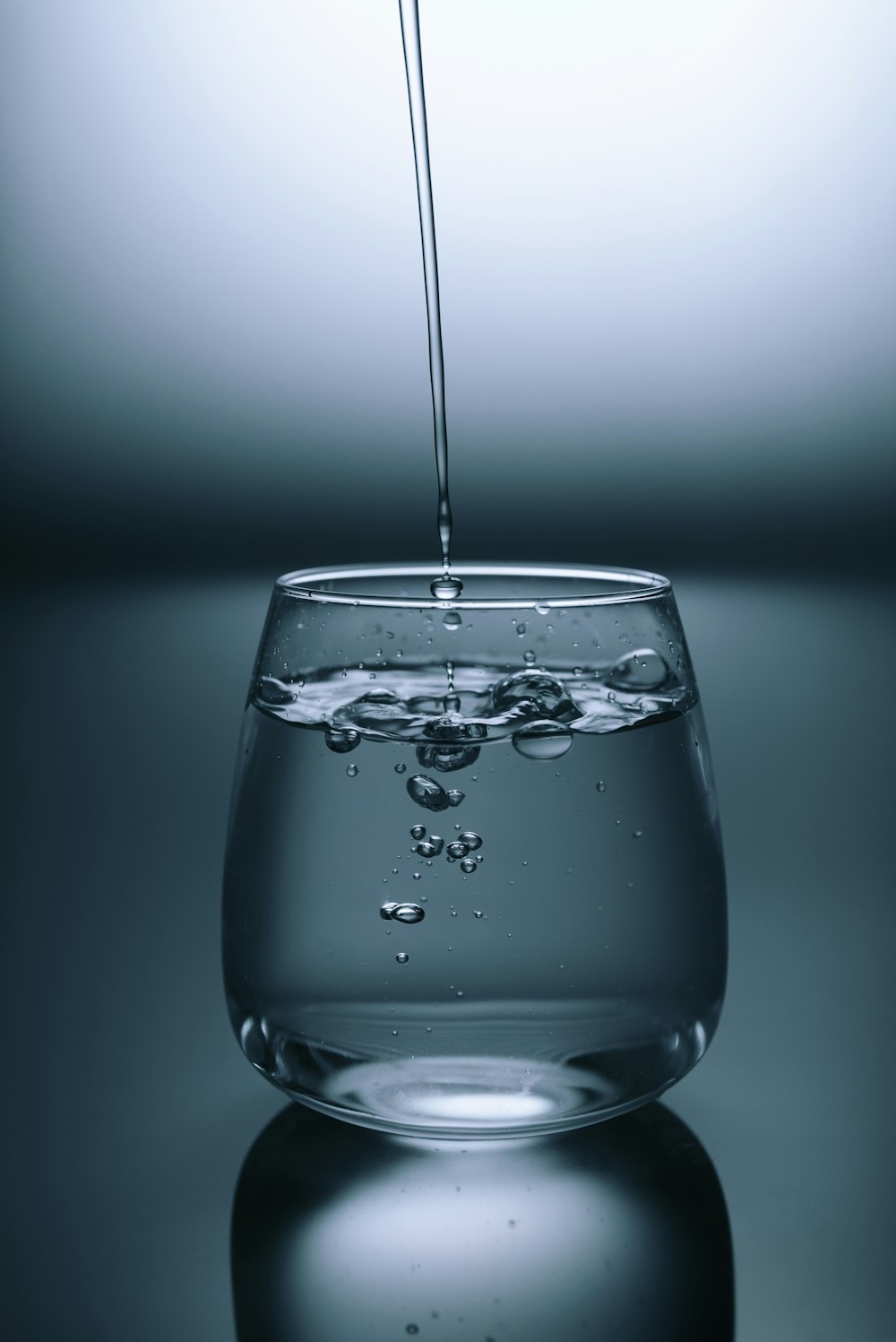 A glass of water next to a bowl of warm bone broth.