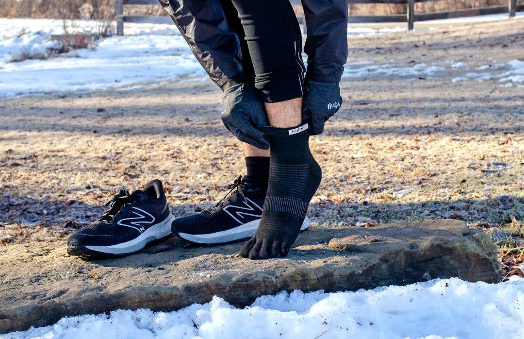 Close-up of a runner pulling on technical performance toe-socks designed for long-distance running.