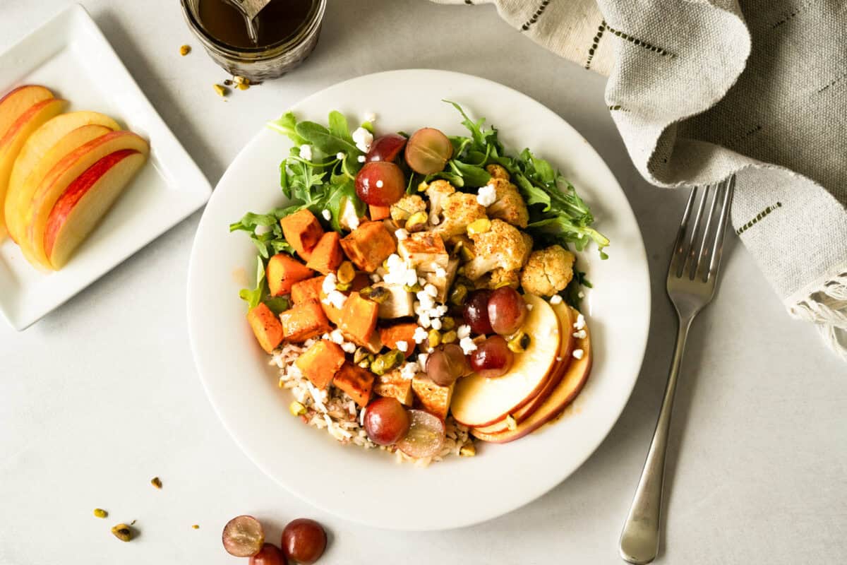 A completed nourish bowl featuring wild rice and chicken with a balsamic dressing.