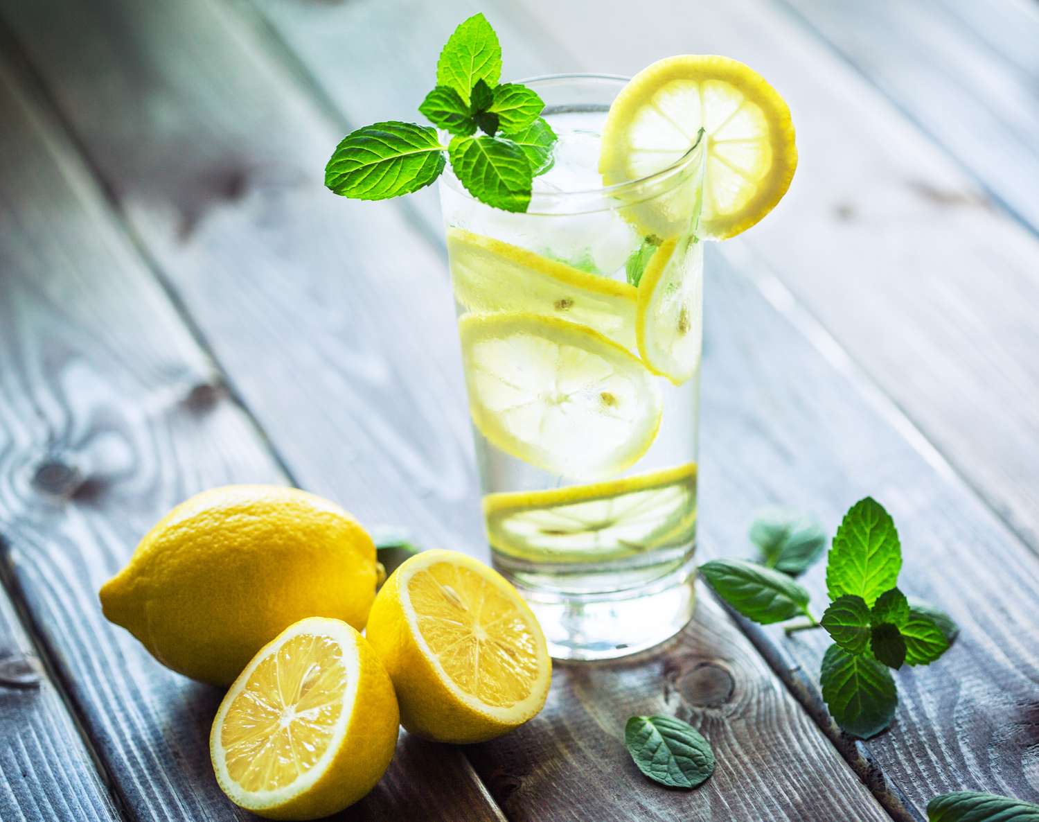 A clear glass of water with fresh lemon slices and juice, illustrating a 25% concentration mixture.