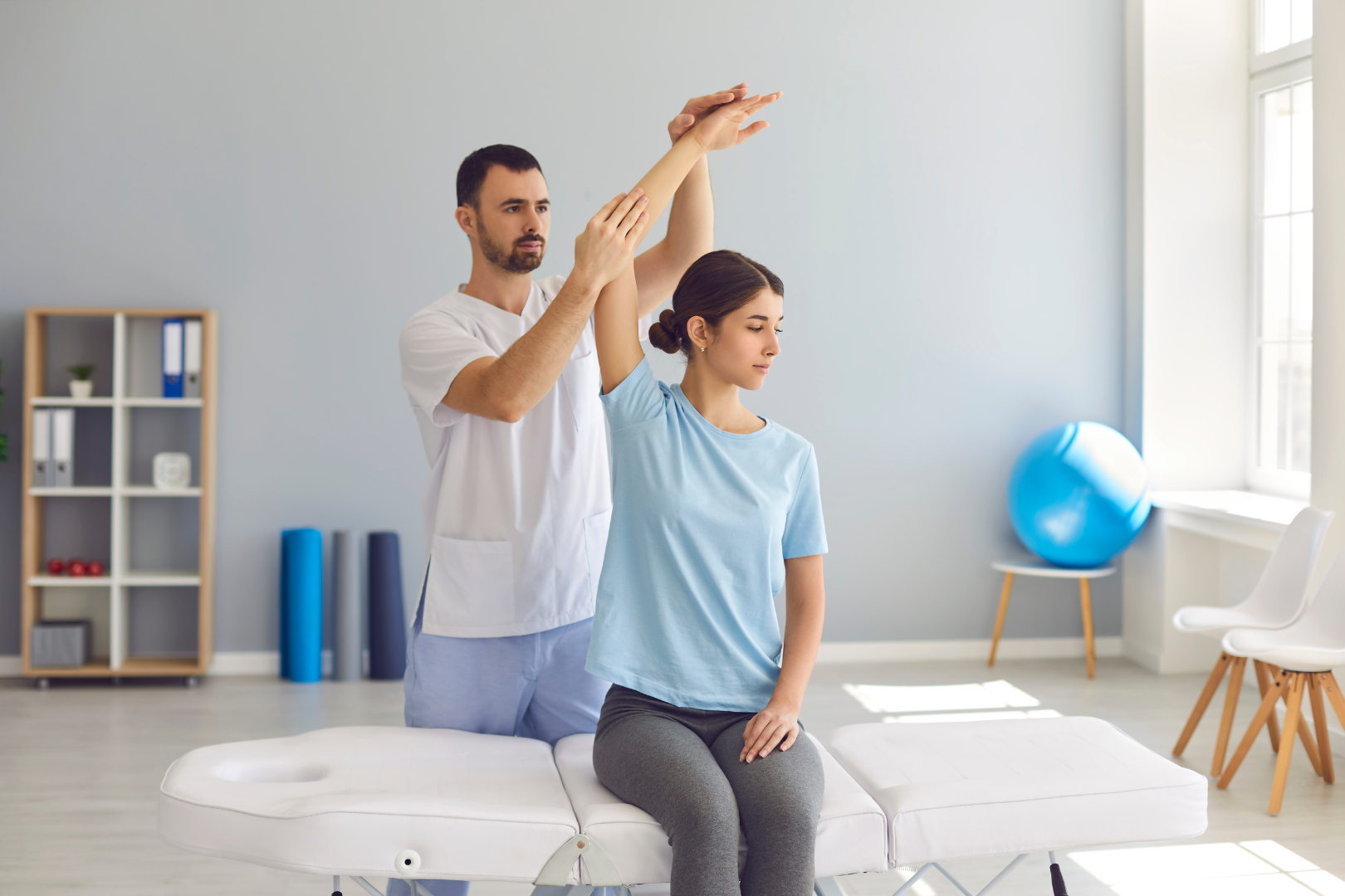 A healthcare professional performing a manual spinal adjustment on a patient lying on a treatment table.
