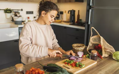 A woman preparing fresh vegetables on a wooden cutting board in a modern kitchen.