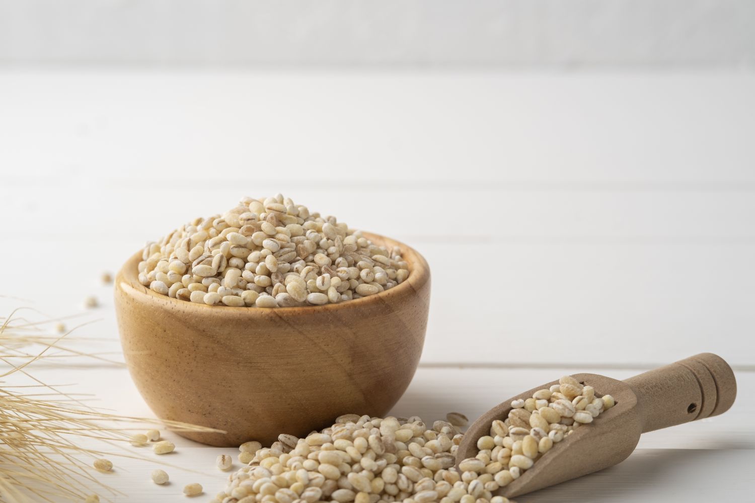 A wooden bowl containing uncooked barley grains, representing low-glycemic food choices.