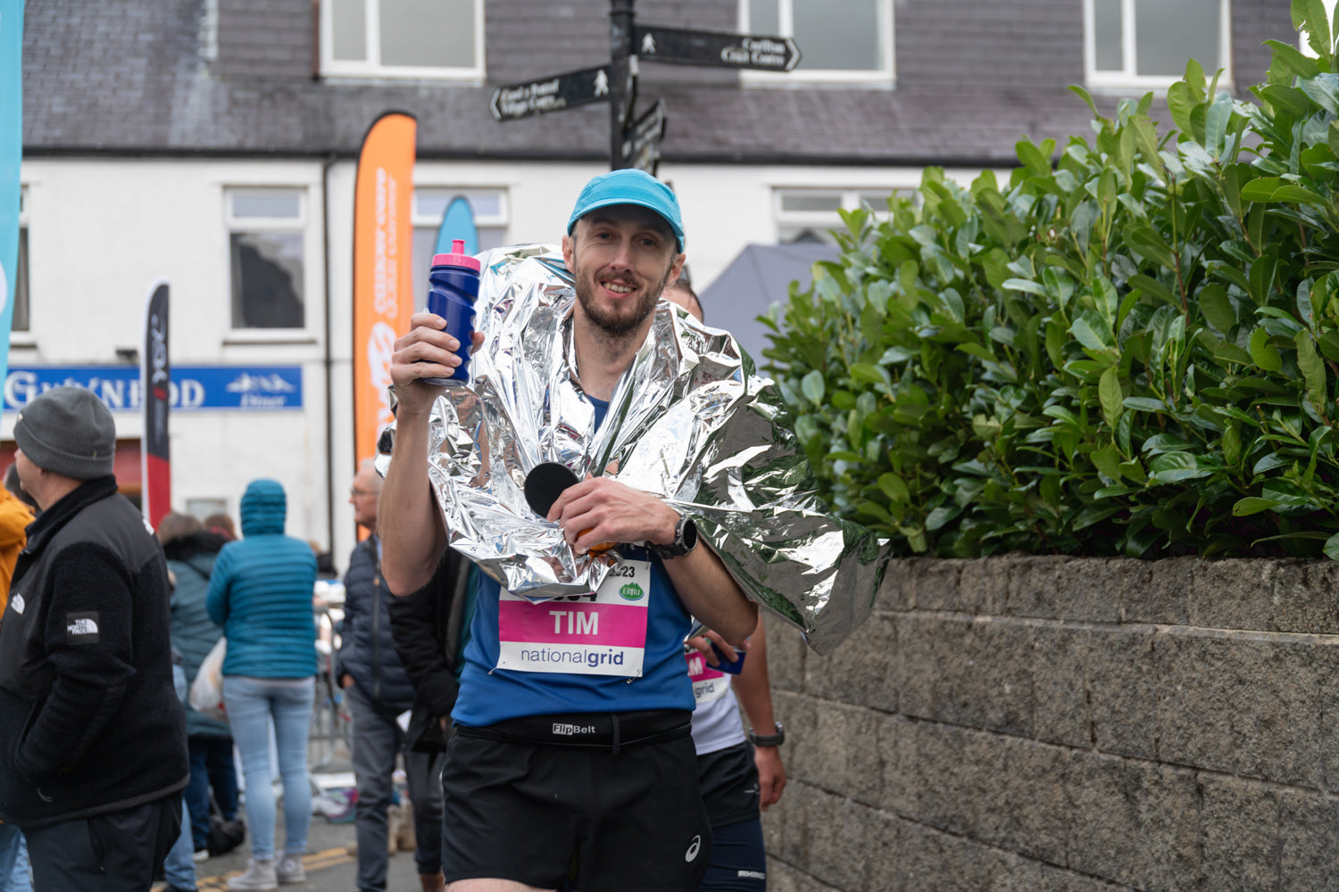 A runner with arms raised in celebration crossing a marathon finish line.