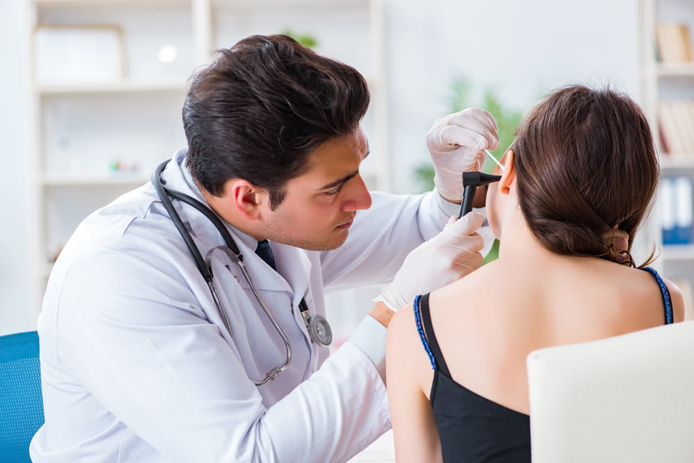 An audiologist in a clinical setting conducting a hearing test with a patient.