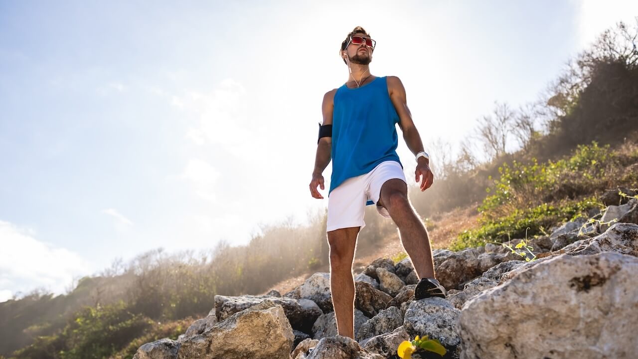 An active man standing outdoors on rocks symbolizing vitality and endurance.