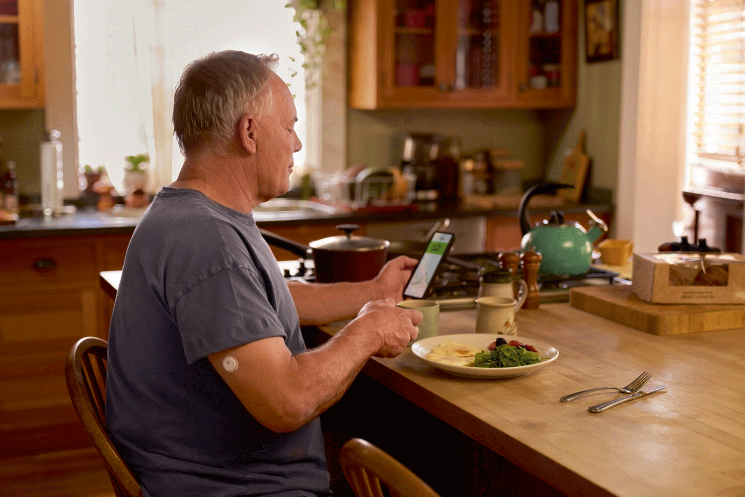 A FreeStyle Libre 3 sensor next to a smartphone showing a real-time glucose trend graph.