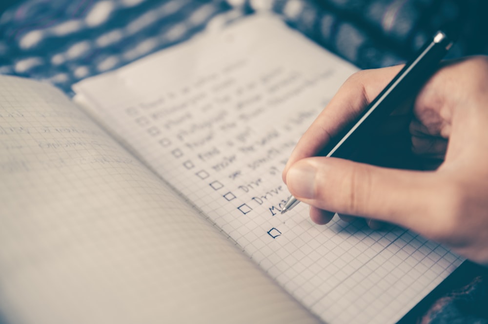A person writing in a food diary next to a prepared meal.