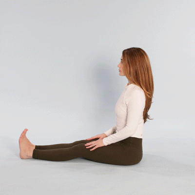 A person demonstrating a seated spinal stretch on a chair to relieve lower back tension.