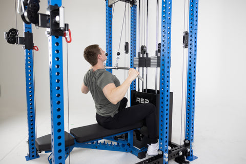 A man performing lat pulldowns with visible muscle engagement in the back.