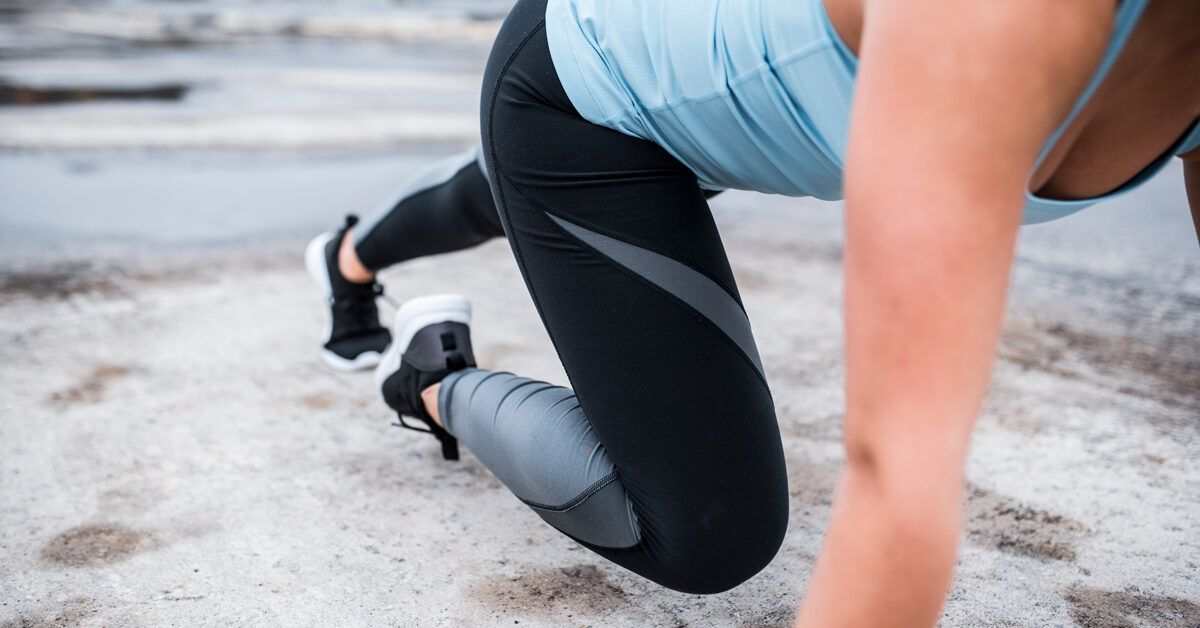 A woman in athletic wear performing a plank on a textured outdoor surface to build core stability.
