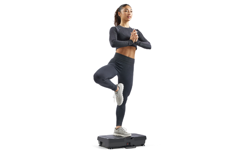 A person performing stretching exercises while sitting or leaning on a vibration platform.