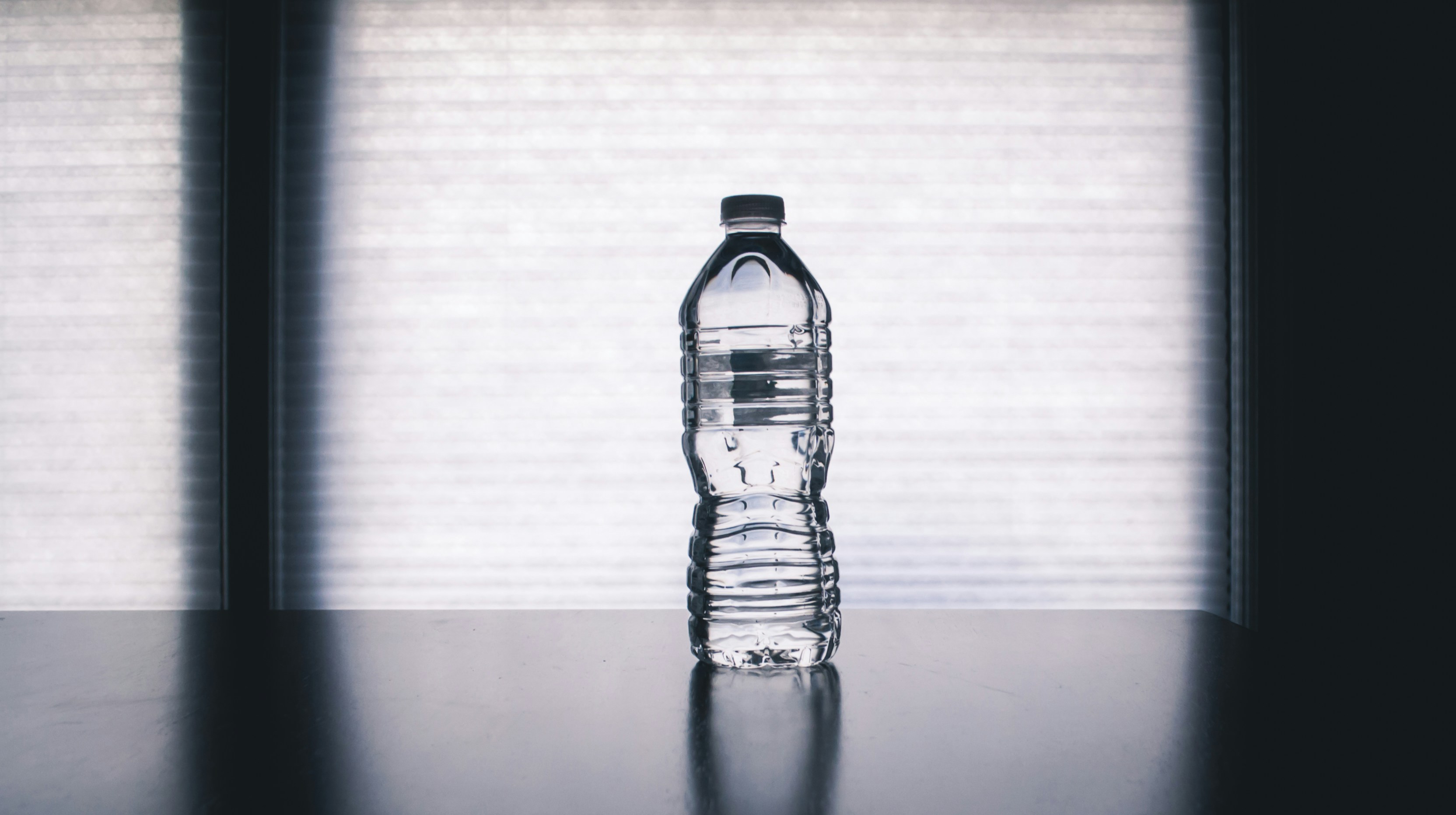 A glass of clear water with fresh lemon slices on a bright surface.