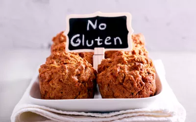 Four gluten-free muffins on a plate with a sign indicating they are gluten-free.