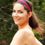 A runner wearing a pink moisture-wicking headband and athletic attire outdoors.