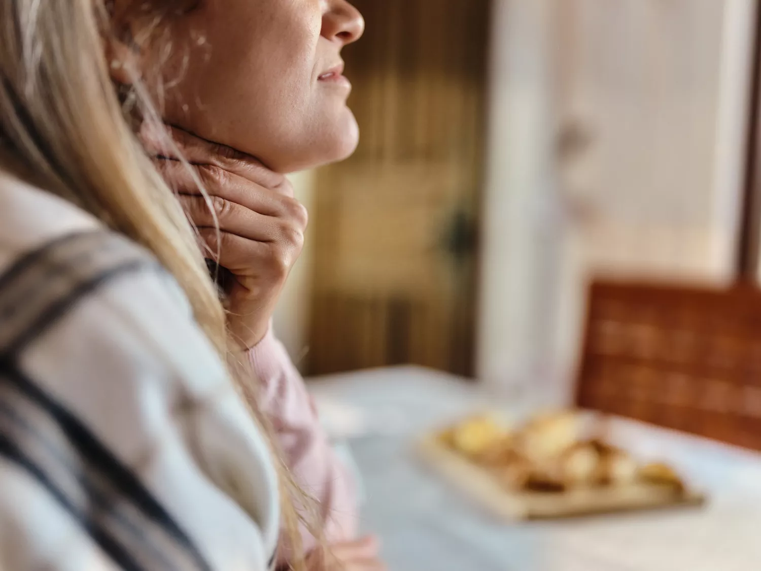 A person holding their throat, suggesting discomfort or issues related to sleep apnea.