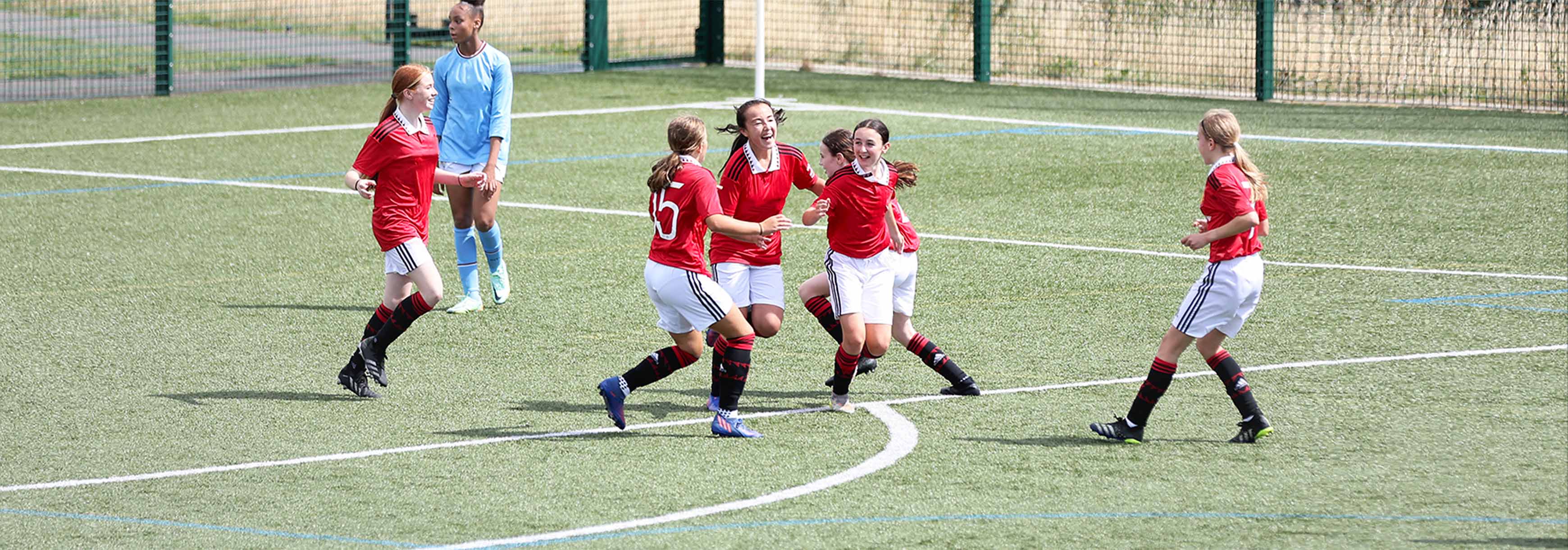 A group of female teammates laughing and celebrating a goal together.