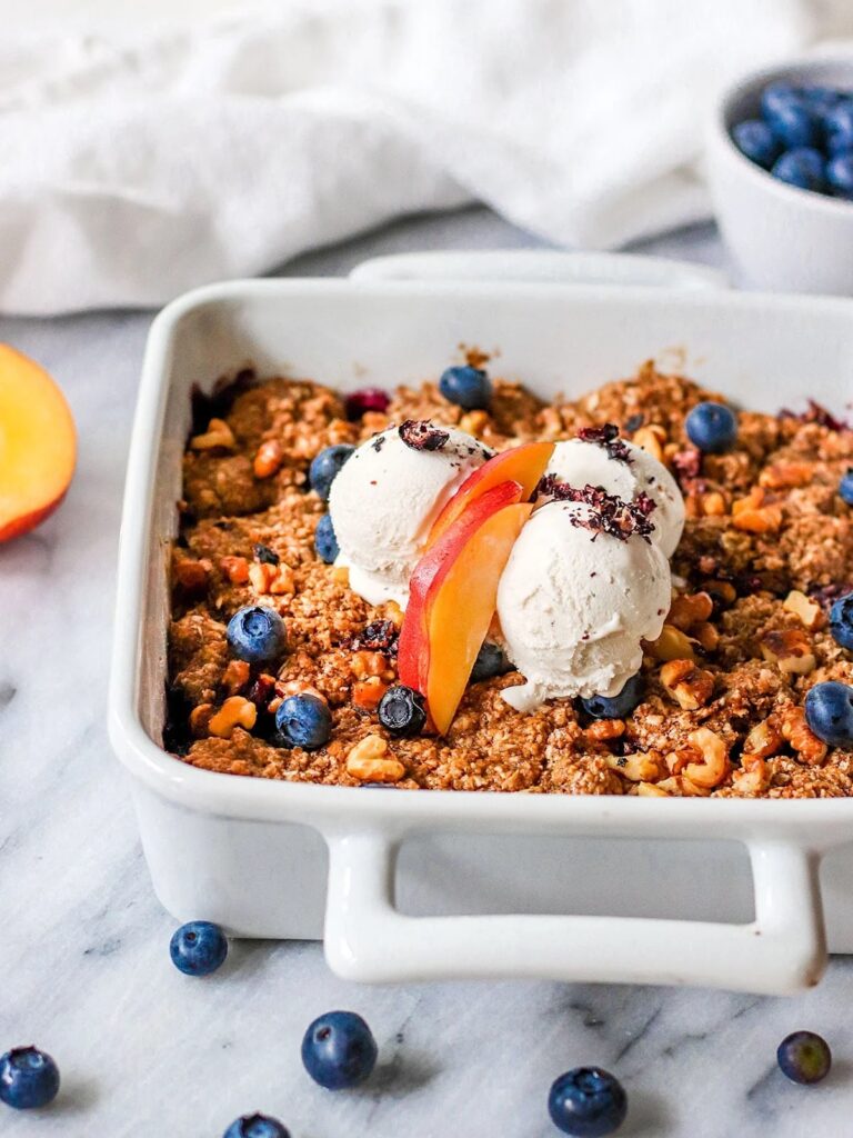 A vegan fruit crisp featuring sliced nectarines and blueberries with an oat topping.