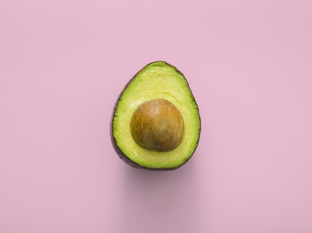 A sliced fresh avocado next to a bowl of mixed nuts.