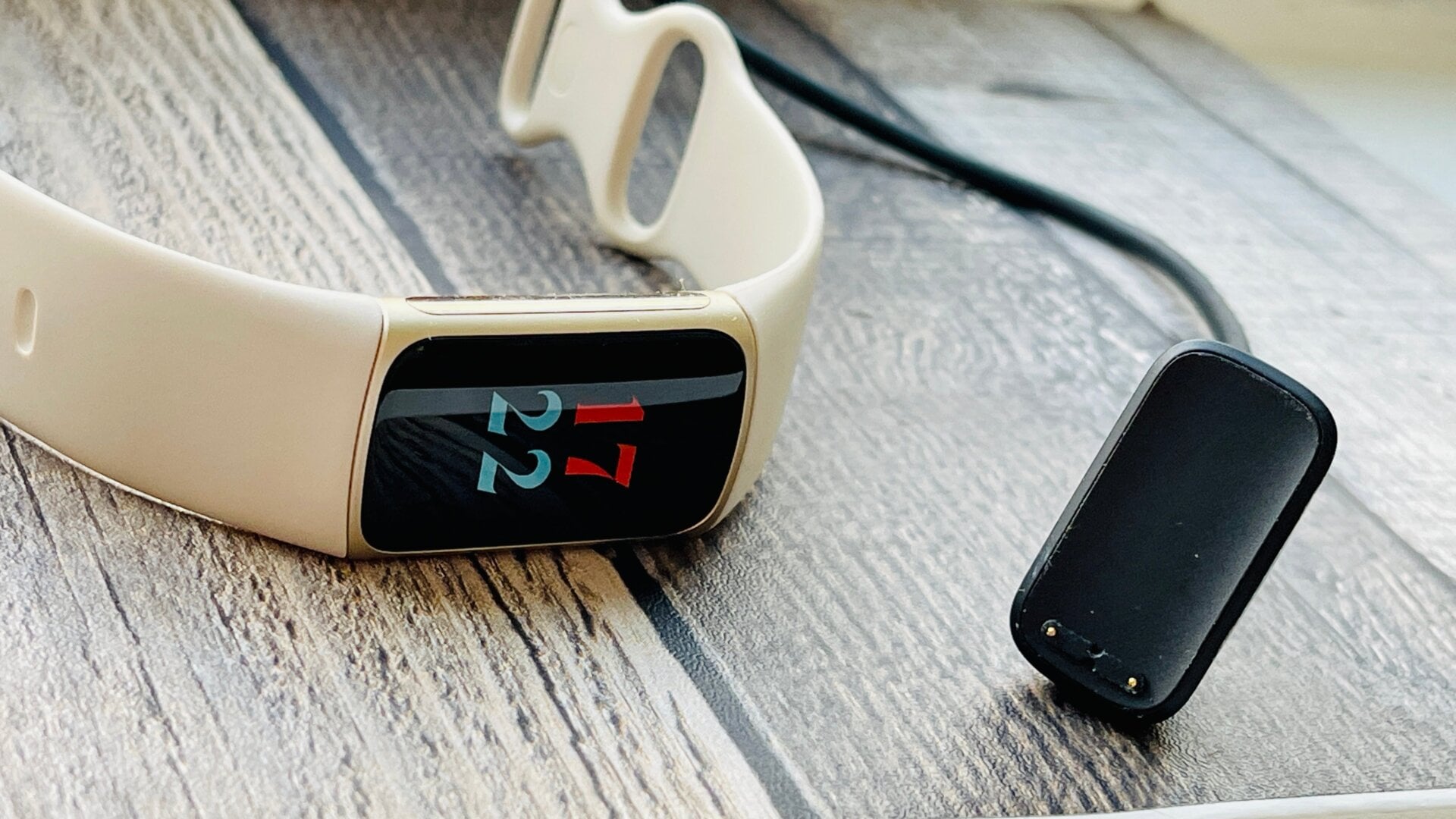 Fitbit Charge 5 connected to its proprietary magnetic charging cable.