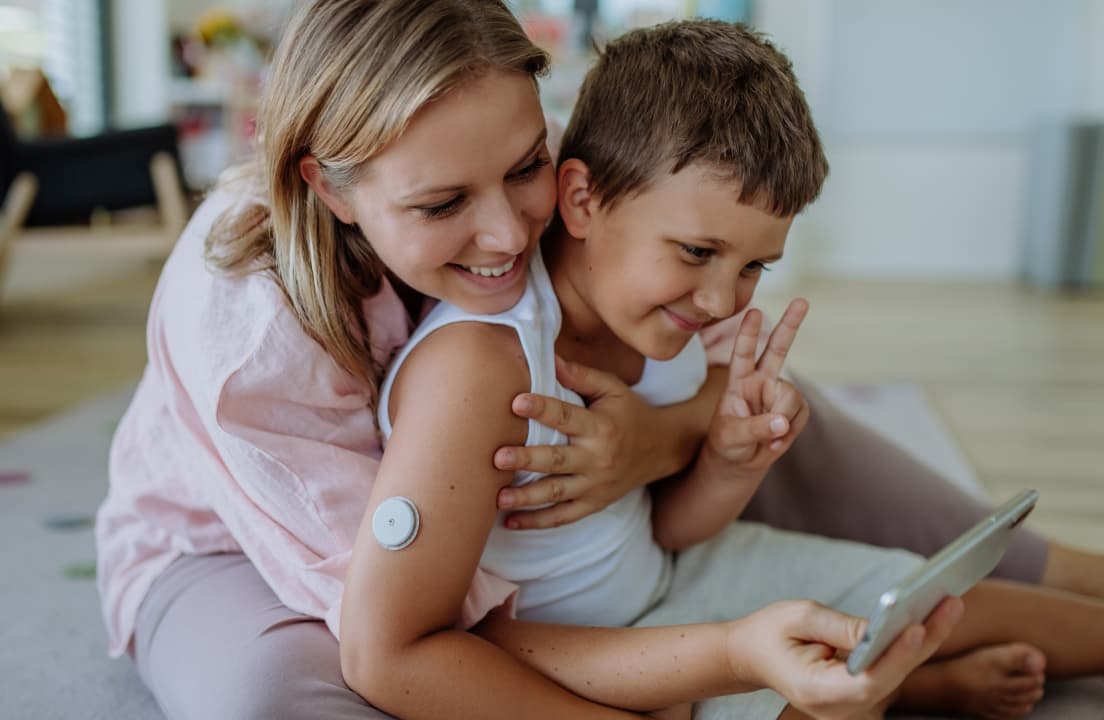 A mother and her young son looking at health data on a smartphone together.