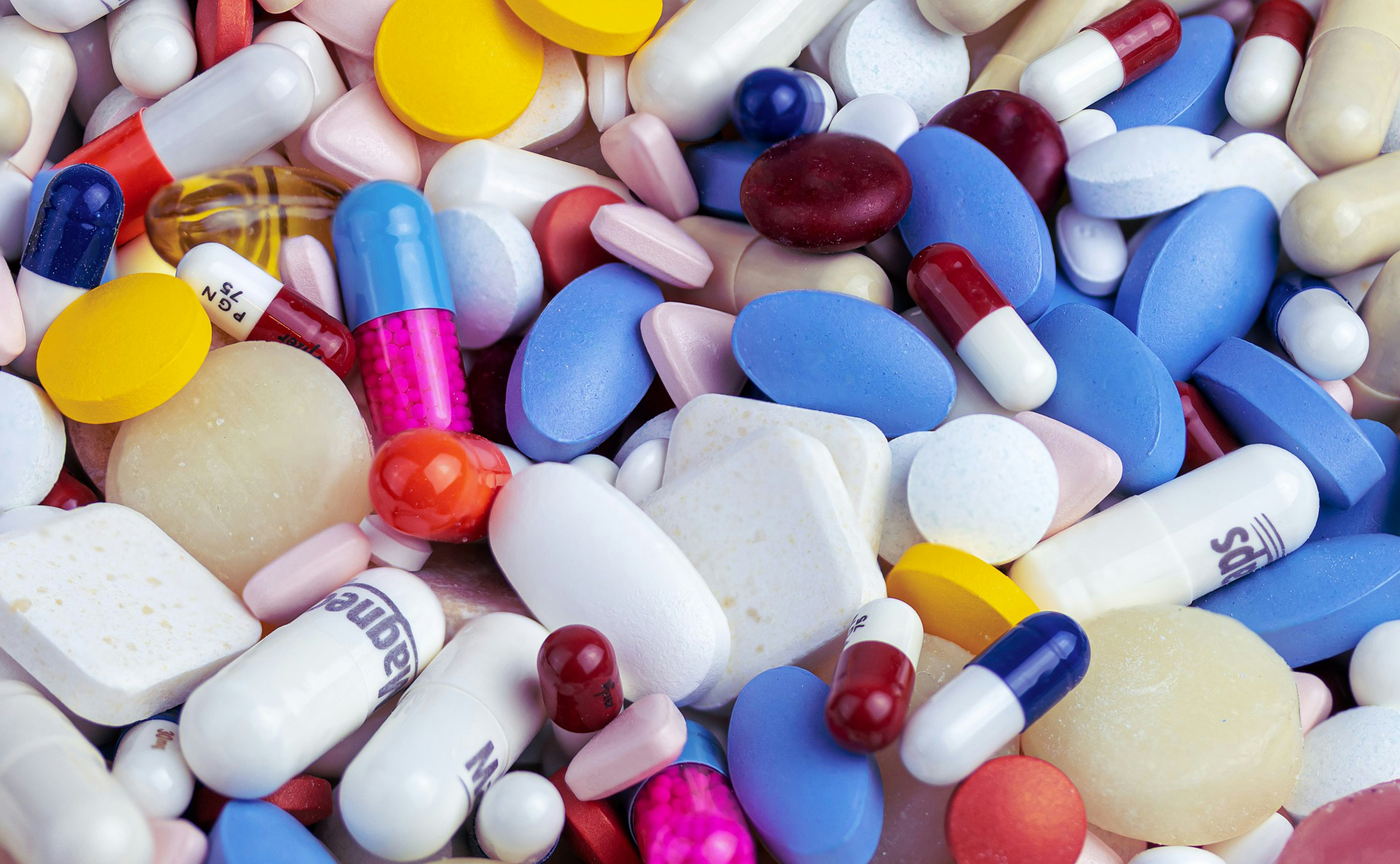 A collection of white medicine capsules and round supplement tablets.