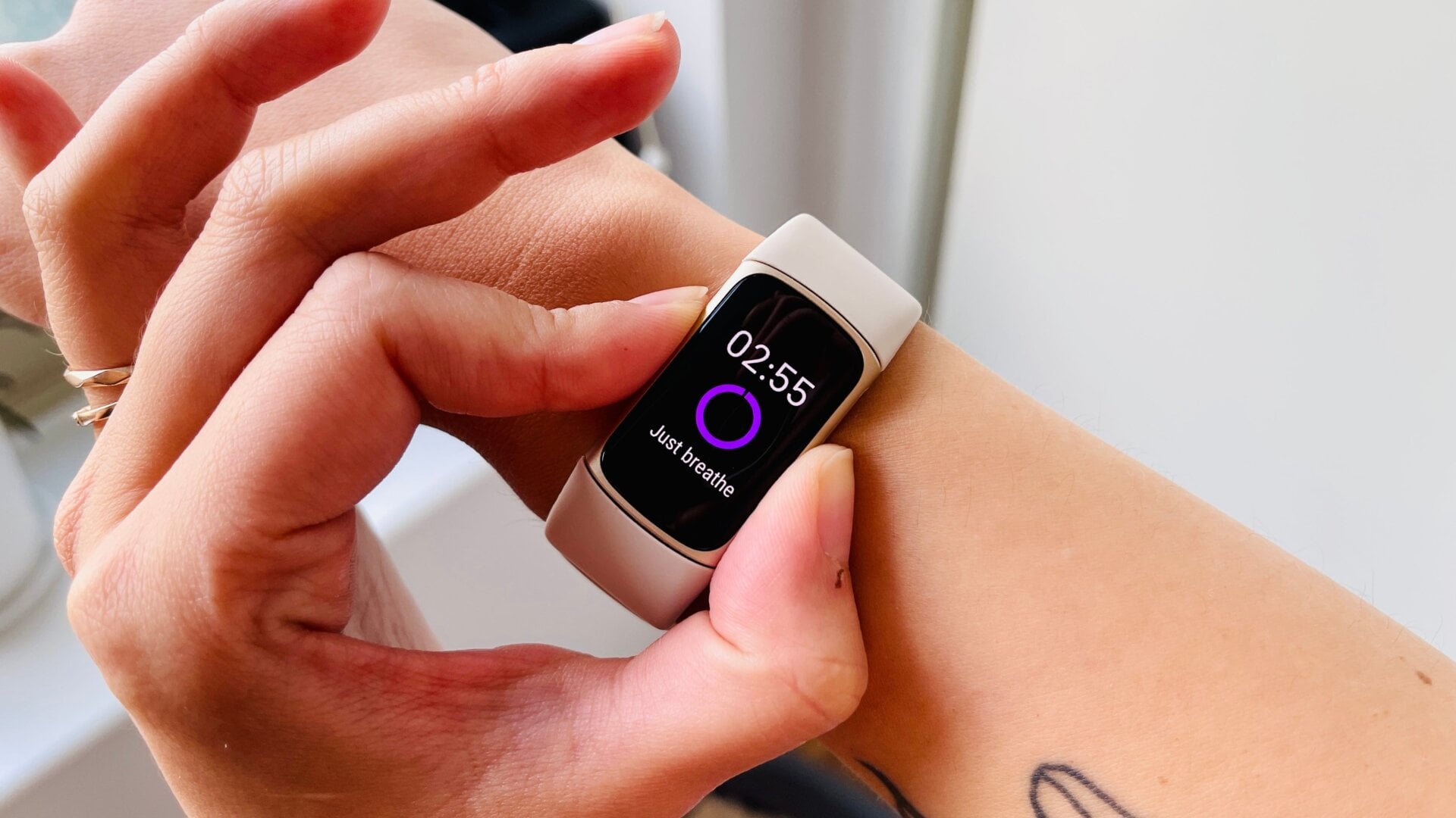 A person holding the sides of the Fitbit Charge 5 to conduct an EDA stress scan.