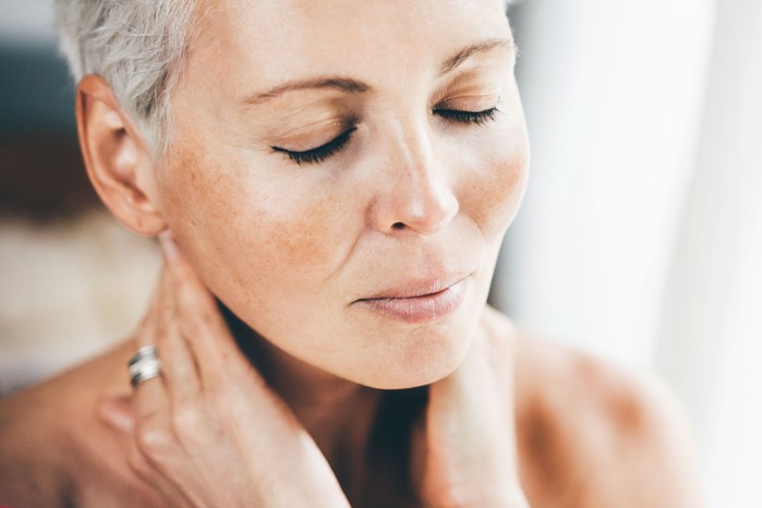 Portrait of a middle-aged woman with smooth, radiant skin and a healthy glow.