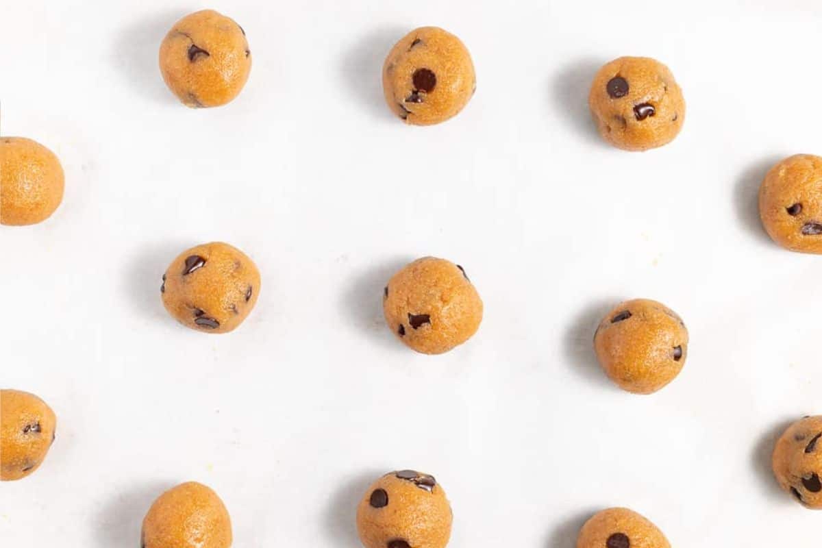 Raw vegan cookie dough balls placed evenly on a parchment-lined baking tray.