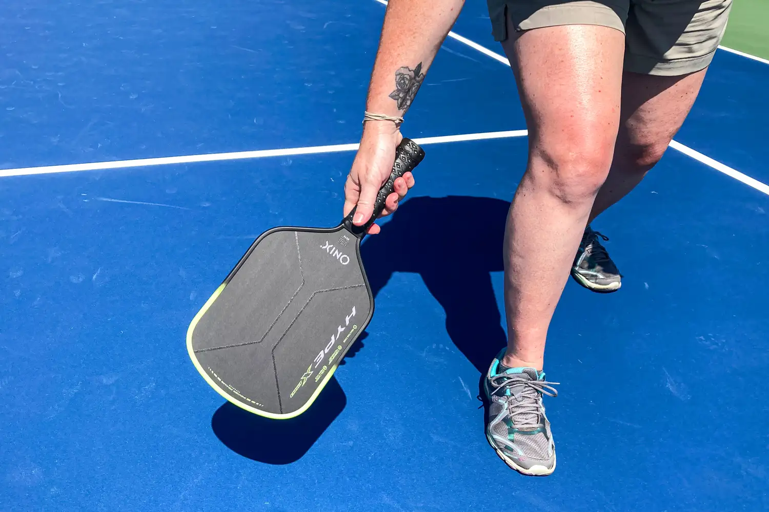 A player in mid-swing using an Onix carbon fiber paddle on a pickleball court.
