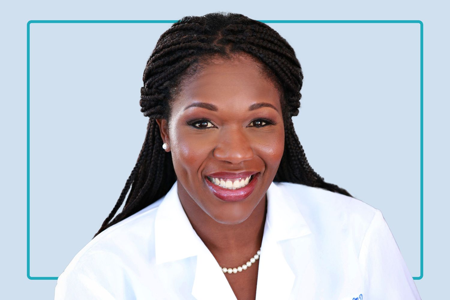 A professional healthcare provider in a white lab coat smiling in a clinical setting.